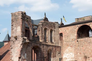 ChatGPT şöyle dedi: HEIDELBERG, ALMANY - 19 Mayıs 2018: Heidelberg Kalesi 'nin yıpranmış taş duvarları ve üzerinde bayrak olan korunmuş kemerlerinin dış görünüşü. Yüksek kalite fotoğraf