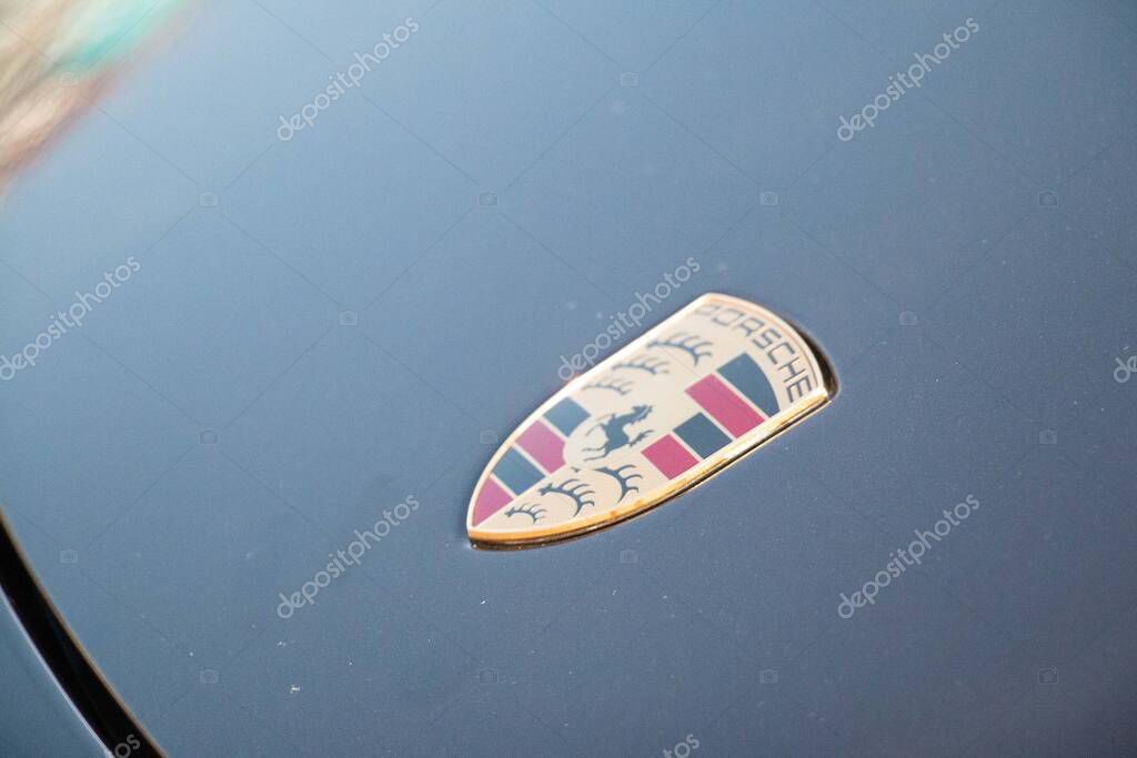 LEIPZIG, GERMANY - AUGUST 18, 2018: Close-up of a Porsche logo on the hood of a blue car reflecting the sky. High quality photo