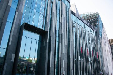 LEIPZIG, GERMANY - 18 Ağustos 2018: Leipzig Üniversitesi 'ndeki Paulinum binasının modern cam cephesi gökyüzünü ve çevreyi yansıtıyor. Yüksek kalite fotoğraf