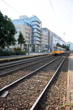 LEIPZIG, ALMANY - 19 AĞUSTOS 2018: Sarı bir banliyö treni bir yaz günü modern bir konut binasının yanında tren raylarından geçer. Yüksek kalite fotoğraf