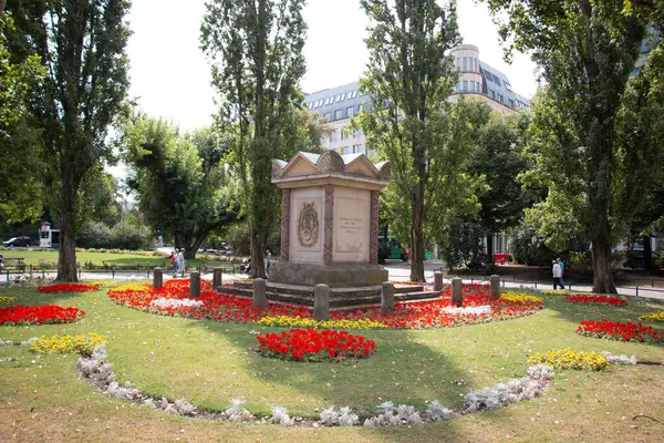  LEIPZIG, ALMANY - 18 AĞUSTOS 2018: Parlak gökyüzünün altında bir anıtı ve renkli çiçek tarlaları olan bir park. Yüksek kalite fotoğraf