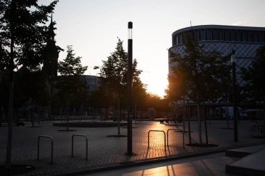  LEIPZIG, ALMANY - 18 Ağustos 2018: Günbatımında veya gündoğumunda modern binalar ve ağaçlarla birlikte bir şehir meydanı. Yüksek kalite fotoğraf