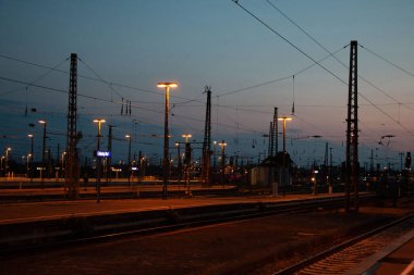  LEIPZIG, ALMANY - 18 AĞUSTOS 2018: Arka planda ışıklı şehir ışıklarıyla alacakaranlıkta ya da şafakta demiryolu rayları ve tepe çizgileri. Yüksek kalite fotoğraf