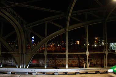 Münih 'teki Hackerbruecke demiryolu köprüsünün ön planda şehir ışıkları ve metal yapılarla gece görüşü. Yüksek kalite fotoğraf