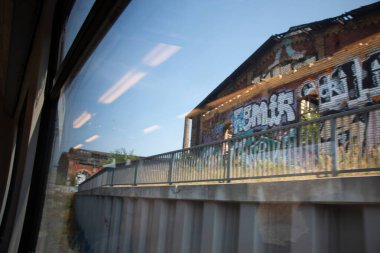 LEIPZIG, GERMANY - 19 AĞUSTOS 2018: Terk edilmiş binaları olan ve Leipzig Hauptbahnhof yakınlarında duvarları grafiti kaplı eski Postbahnhof 'a tren penceresinden bakmak