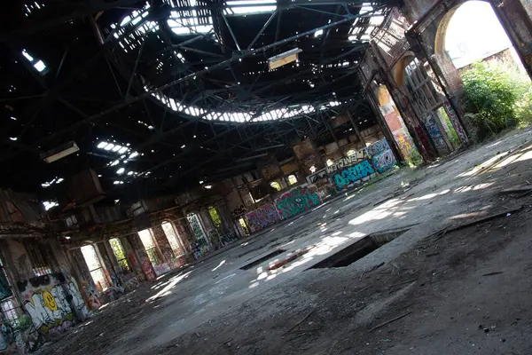  LEIPZIG, GERMANY - 19 AĞUSTOS 2018: Yıkılan çatısı ve Alter Postbahnhof 'ta grafitisi olan uçsuz bucaksız, terk edilmiş bir sanayi salonunun iç görünümü. Yüksek kalite fotoğraf