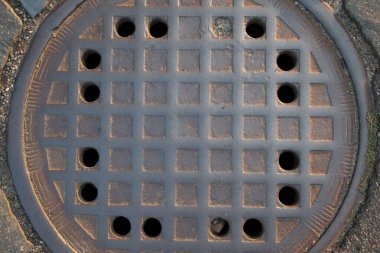  Çakıl taşı sokağına demir rögar kapağı dökün. Sıcak, hafif kentsel desenli. Yüksek kalite fotoğraf