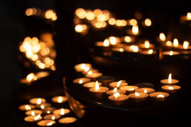 Karanlıkta parlayan adak mumları dinsel bir resimde sıcacık bokeh etkisi yaratıyor.