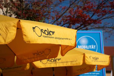 HAAG OBERBAYERN, GERMANY - 26 Ekim 2018: Rosolar, Rosenheimer Solarfoerderverein ile damgalanmış sarı şemsiyeler, açık mavi gökyüzü altında yerel Emobilitaetstag etkinliği sırasında kuruldu. Yüksek kalite fotoğraf