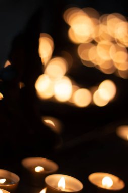 Dini bir ortamda sıcacık bokeh efektiyle karanlıkta parlayan birden fazla adak mumları. Yüksek kalite fotoğraf