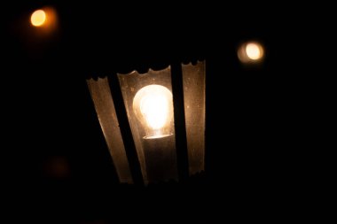  Karanlık dikey çizgilerle çerçevelenmiş sıcak, parlayan bir ampul. Yüksek kalite fotoğraf