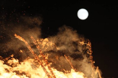  Gece ve ışıkta, uzak bir şenlik ateşinin üzerinde parlak ay. Yüksek kalite fotoğraf