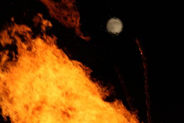  Gece ve ışıkta, uzak bir şenlik ateşinin üzerinde parlak ay. Yüksek kalite fotoğraf