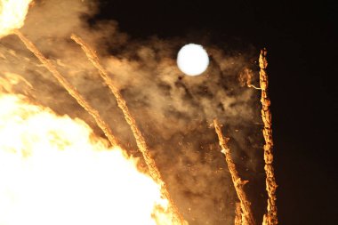  Gece ve ışıkta, uzak bir şenlik ateşinin üzerinde parlak ay. Yüksek kalite fotoğraf