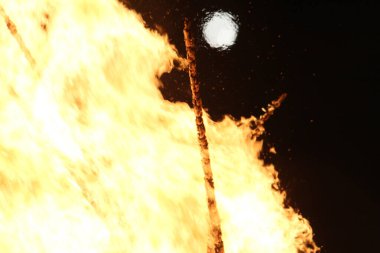  Geceleyin parlak turuncu alevlerle dolu büyük bir şenlik ateşinin üzerinde dolunay. Yüksek kalite fotoğraf