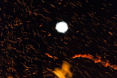  Geceleyin parlak turuncu alevlerle dolu büyük bir şenlik ateşinin üzerinde dolunay. Yüksek kalite fotoğraf