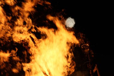  Geceleyin parlak turuncu alevlerle dolu büyük bir şenlik ateşinin üzerinde dolunay. Yüksek kalite fotoğraf