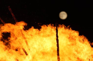  Geceleyin parlak turuncu alevlerle dolu büyük bir şenlik ateşinin üzerinde dolunay. Yüksek kalite fotoğraf