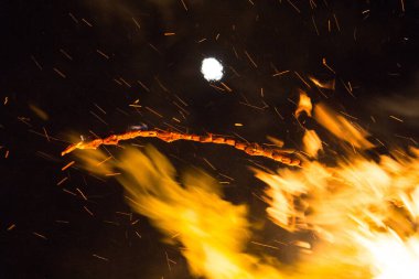  Geceleyin parlak turuncu alevlerle dolu büyük bir şenlik ateşinin üzerinde dolunay. Yüksek kalite fotoğraf