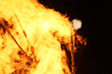  Geceleyin parlak turuncu alevlerle dolu büyük bir şenlik ateşinin üzerinde dolunay. Yüksek kalite fotoğraf