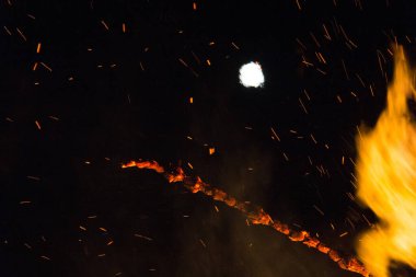  Geceleyin parlak turuncu alevlerle dolu büyük bir şenlik ateşinin üzerinde dolunay. Yüksek kalite fotoğraf