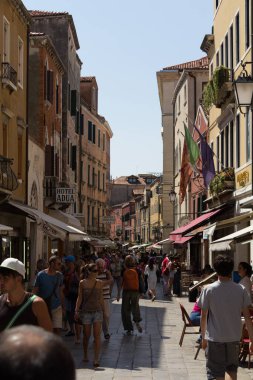 Venedik, İtalya - 24 Ağustos 2013: Venedik 'in merkezinde tarihi binalar ve hediyelik eşya tezgahlarıyla dolu kalabalık bir alışveriş caddesinden geçen turist kalabalığı. Yüksek kalite fotoğraf