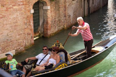 VENICE, İtalya - 24 AĞUSTOS 2013: Gondolcu turistlerle dolu bir gondolu tarihi tuğla binaların yanındaki dar bir kanala doğru sürüyor. Yüksek kalite fotoğraf