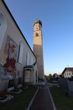 RECHTMEHRING, ALMANY - 31 Mayıs 2025: Yüksek kulesi ile Rechtmehring kilisesi geniş açılı görüş ve canlı bir akşam gökyüzü altında kemerli giriş. Yüksek kalite fotoğraf