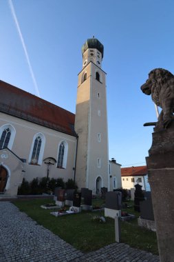 RECHTMEHRING, ALMANY - 31 Mayıs 2025: Yüksek kulesi ile Rechtmehring kilisesi geniş açılı görüş ve canlı bir akşam gökyüzü altında kemerli giriş. Yüksek kalite fotoğraf