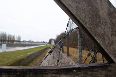 DACHAU, GERMANY - NOVEMBER 25, 2017: Diagonal view along the barbed wire fence and guard tower at Dachau concentration camp memorial site. High quality photo