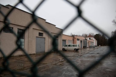 DACHAU, GERMANY - NOVEMBER 25, 2017: View through fence of former industrial buildings at Dachau concentration camp site on a rainy day. High quality photo