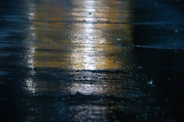 Geceleri ıslak asfaltta renkli sokak ışıklarının yansıması. Yüksek kalite fotoğraf