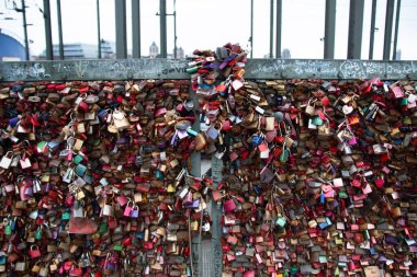Aşk kilitleri Köln 'deki Hohenzollern Köprüsü' ndeki korkuluklara bağlı ve arka planda şehrin silüeti var. Yüksek kalite fotoğraf