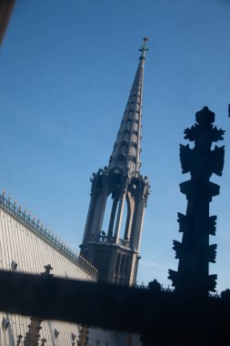 Gotik kilise, açık mavi gökyüzüne karşı ön planda çapraz silueti olan bir kule gibi. Yüksek kalite fotoğraf