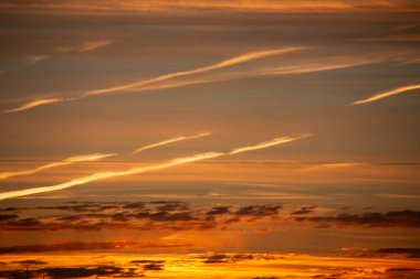 ChatGPT der ki: Ufukta katmanlı bulutlar ve dramatik ışık çizgileri olan canlı turuncu ve altın renkli günbatımı gökyüzü. Yüksek kalite fotoğraf