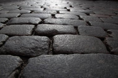 Sert yüzey dokusuna sahip kuru kaldırım taşları karamsar alçak perspektifte açılı ışıkla aydınlatılıyor. Yüksek kalite fotoğraf