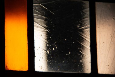 Arkasından aydınlatılmış, turuncu, beyaz ve siyah cam parçalı, soyut bir pencerenin yakın plan görüntüsü. Yüksek kalite fotoğraf