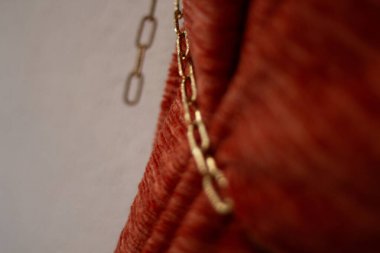 Sade duvara asılı kırmızı kumaş üzerinde asılı altın zincir yakın çekim. Yüksek kalite fotoğraf