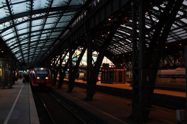 COLOGNE, ALMANY - 29 ARALIK 2017: Bölgesel tren, Köln Merkez İstasyonu 'nun çelik ve cam çatısının altındaki platforma akşam karanlığında ulaşır. Yüksek kalite fotoğraf