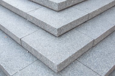 Temiz geometrik çizgiler ve gri yüzey dokusuyla istiflenmiş granit taş basamakların detaylı görüntüsü. Yüksek kalite fotoğraf