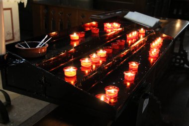 MÜZİK, GERMANE - 24 HAZİRAN 2025: Münih 'teki loş bir kilisenin içindeki dua standına adak mumları konuldu. Yüksek kalite fotoğraf