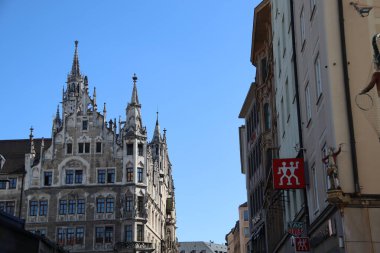 MÜZİK, GERMANE - 24 Haziran 2025: Münih 'in tarihi merkezinde dar bir caddeden Eski Şehir Salonu' nun neo-gotik cephesinin görüntüsü açık mavi gökyüzü altında. Yüksek kalite fotoğraf