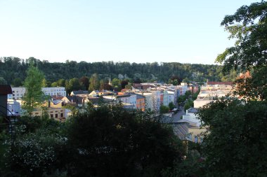 WASSERBURG AM Hanı, GERMANY - 20 Haziran 2025: Wasserburg am Inn 'in ağaçlarla çevrili renkli binaları ve akşam vakti orman tepeleri ile yükseltilmiş manzarası. Yüksek kalite fotoğraf