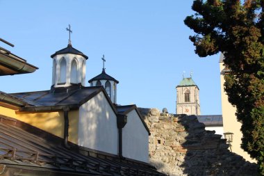 WASSERBURG AM Hanı, GERMANY - 20 Haziran 2025: Wasserburg am Inn 'deki çatılar ve dini kuleler ön planda taş duvar harabeleri ve arka planda St. Jakob kilise kulesi
