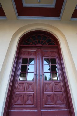 WASSERBURG AM Hanı, ALMANY - 20 Haziran 2025: Geometrik panelli ve gökyüzü ve ağaçların yansımaları olan kemerli kırmızı ahşap kilise kapısının yakın görüntüsü. Yüksek kalite fotoğraf