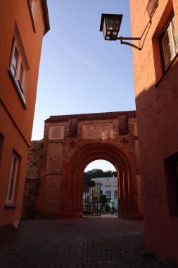 ChatGPT şunları söyledi: WASSERBURG AM INN, GERMANY - 20 Haziran 2025: Tarihi kemer yolu ve çevresindeki turuncu binalar eski kasabadaki sıcak akşam ışığı ile aydınlatıldı. Yüksek kalite fotoğraf