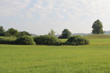 KIRCHDORF, ALMANY - 19 Haziran 2025: Kirchdorf köy kilisesi ve Lerchenberg 'den açık gökyüzü ve ön plan silüetiyle görünen çatılar. Yüksek kalite fotoğraf
