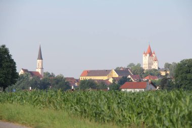 HAAG OBERBAYERN, Almanya - 19 Haziran 2025: Haager Schlossturm ve köy kilisesinin açık bir yaz gününde mısır tarlaları üzerinde yükselişinin manzarası. Yüksek kalite fotoğraf