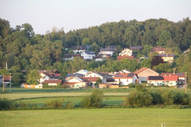 SOYEN, GERMANY - 11 Haziran 2025: Altın saat boyunca arka planda evleri, yeşil çayırları ve orman tepeleri olan Soyen köyünün manzarası yükseldi. Yüksek kalite fotoğraf
