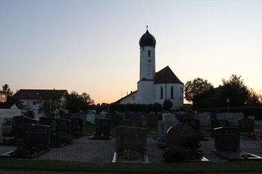 SoYEN, Almanya - 11 HAZİRAN 2025: St. Petrus kilisesi ve Soyen köyündeki gün batımında etrafındaki mezarlığın manzarası. Yüksek kalite fotoğraf